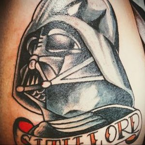 Фото тату Дарта Вейдера с надписью "Sith Lord" на плече. Детализированный рисунок в стиле реализм.