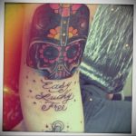 Фото татуировки Дарта Вейдера в стиле сахарной черепушки (sugar skull) на руке. Изображение выполнено в ярких цветах с использованием розового, оранжевого и синего.