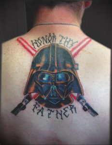 Фото тату Дарта Вейдера на спине с надписью 'Honor Thy Father'. Черно-красный рисунок татуировки в стиле олдскул.