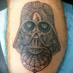 Фото татуировки в стиле Sugar Skull с изображением черепа Дарта Вейдера. Череп украшен яркими узорами и цветами, а в глазницах расположены бриллианты.