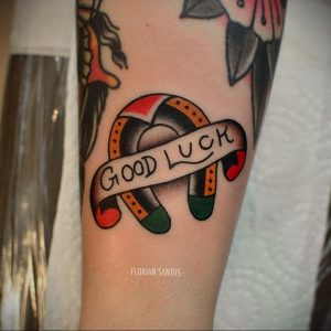 Фото тату подковы с надписью 'Good Luck' в стиле олд скул на руке. Яркие цвета, четкие контуры, символика удачи и позитива.