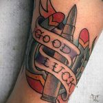 Фото тату патронов с надписью 'Good Luck'. Традиционный стиль, яркие цвета, четкие контуры. Символ удачи и защиты.