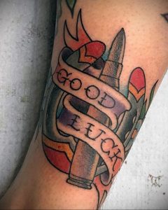 Фото тату патронов с надписью 'Good Luck'. Традиционный стиль, яркие цвета, четкие контуры. Символ удачи и защиты.