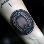 Фото тату подковы в стиле black and grey на предплечье. Реалистичный рисунок, детализированная проработка, эффект металла.