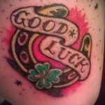 Фото тату в стиле олд скул с изображением подковы, клевера и надписи 'Good Luck' на руке.