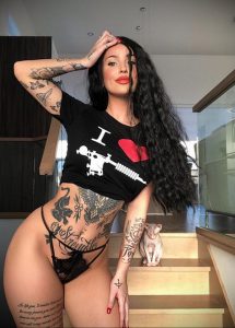 Фотография девушки в футболке и с татуировками на теле, демонстрирующая стильные рисунки и привлекательный образ.