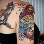 Фото тату лисы и попугая на женской спине и плече. Рисунок выполнен в ярких цветах с использованием тонких линий и детализации.