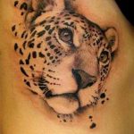 Фото тату: реалистичный рисунок головы леопарда на плече, выполненный в черно-серых тонах с брызгами краски.