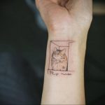 Фото тату с изображением кошки в рамке, напоминающей окно. Черно-белый рисунок с добавлением текста 'My muse'.