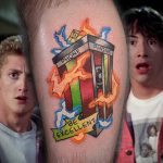 Фото тату на руке с изображением телефонной будки из фильма 'Bill & Ted's Excellent Adventure', выполненное в ярком и красочном стиле.