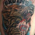 Фото тату медведя с надписью 'BRUINS' и логотипом хоккейной команды на плече. Яркие цвета и динамичный рисунок.