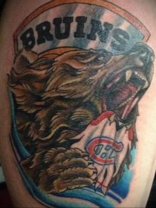 Фото тату медведя с надписью 'BRUINS' и логотипом хоккейной команды на плече. Яркие цвета и динамичный рисунок.