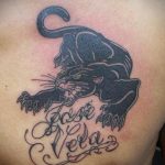 Фото тату черной пантеры на груди с надписью "Rose Vela". Рисунок выполнен в черных тонах с четкими контурами.