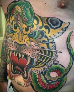Фото татуировки тигра, обвитого змеей, выполненной в стиле олд скул. Яркие цвета и четкие контуры создают эффектный рисунок.