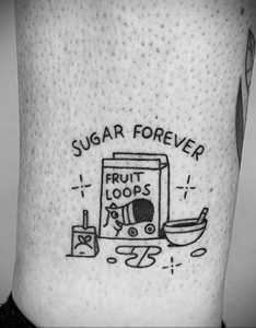 Фото тату: красочная татуировка с изображением коробки хлопьев 'Fruit Loops' и чашки с хлопьями на руке. Рисунок татуировки выполнен в мультяшном стиле.