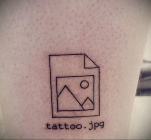 Простая черно-белая татуировка в виде иконки файла с надписью 'tattoo.jpg' на коже. Минималистичный дизайн и юмористический подход.