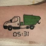 Фото тату с изображением мусоровоза и цифрового времени '05:31'. Оригинальный рисунок на руке.