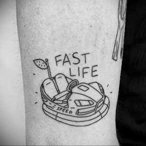 Фото тату в стиле минимализм с изображением автомобиля и надписью 'FAST LIFE'. Черно-белый рисунок на руке.
