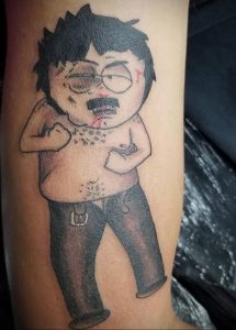 Фото тату: яркий рисунок персонажа Картмана из мультсериала South Park, изображенного в характерной позе с поднятой рукой и кровоточащим лицом.