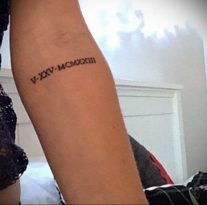 Фото тату: На внутренней стороне предплечья изображены римские цифры 'V-XXV-MCMXXIII' черным цветом, создавая элегантный и запоминающийся рисунок.