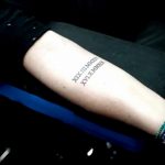 Фото тату: черные римские цифры, расположенные вертикально на запястье, создающие элегантный и сдержанный дизайн.