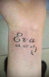 Фото татуировки на руке с именем "Eva", датой рождения "06.07.09" и отпечатком маленькой ножки. Черный цвет, трогательный и значимый рисунок.