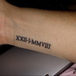 Фото тату: татуировка римскими цифрами 'XXII-I-MMVIII' на запястье. Черный цвет, четкие линии, минималистичный дизайн.
