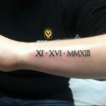 Фото тату: татуировка римскими цифрами 'XI XVI MMXIII' на предплечье. Черный цвет, четкие линии, минималистичный дизайн.