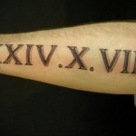 Фото тату: черные римские цифры 'XXIV.X.VIII' на предплечье, выполненные четкими линиями. Минималистичный рисунок татуировки для мужчин и женщин.