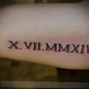 Фото минималистичной татуировки с римскими цифрами X.VII.MMXXII на запястье. Элегантный и сдержанный дизайн.
