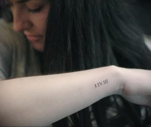 Фото тату: на запястье руки выгравированы римские цифры 'I IV III' черными чернилами. Минималистичный стиль, маленькая татуировка.