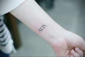 Фото тату: небольшая черная татуировка с римскими цифрами 'XIV' на запястье. Простой и элегантный дизайн, идеально подходит для тех, кто ценит лаконичность.