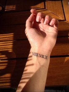 Фото тату: черные римские цифры 'VIII.VIIX' на запястье. Нежный и минималистичный дизайн, идеально подходит для девушек. Тонкие линии и аккуратное исполнение.