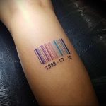 Фото цветной татуировки в виде штрих-кода с датой '1998-07-10' на руке. Яркие цвета, минималистичный дизайн, необычная идея для тату.