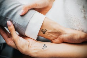 Фото парных татуировок на запястьях с изображением сердца и даты '7716'. Минималистичный дизайн, символизирующий любовь и важную дату для пары.