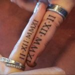 Фото парных тату с римскими цифрами 'II-XII-MMXI IX-WMMXI' на пальцах. Стиль татуировки - минимализм, тонкие черные линии.