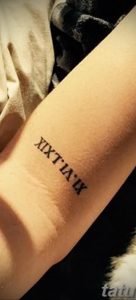 Фото татуировки с римскими цифрами XIX.IV.IX на руке. Простой, элегантный дизайн, выполненный черными линиями.