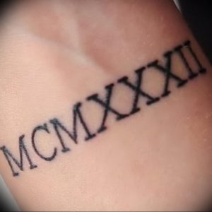 Фото татуировки с римскими цифрами MCMXXII, выполненной на руке. Черный цвет, четкие линии, классический стиль.