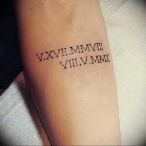 Фото тату: римские цифры 'V.XVII.MMVIII VIII.V.MMX' на предплечье. Четкий рисунок, минималистичный стиль. Идеальный эскиз для памятной татуировки.