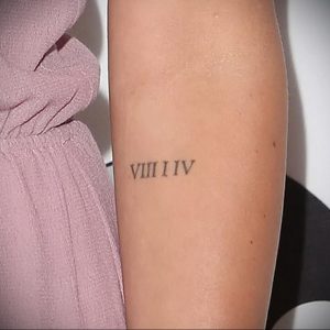 Фото тату: маленькая черная татуировка римскими цифрами VIII I IV на предплечье. Изящный и минималистичный дизайн.
