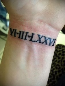 Фото тату: черная татуировка римскими цифрами VI-III-I-LXXVI на запястье. Минималистичный дизайн, символизирующий важную дату.