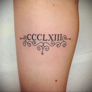 Фото тату: черная татуировка римскими цифрами CCCLXIII на предплечье, украшенная изящными завитками. Минималистичный дизайн для ценителей лаконичности.