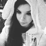 Черно-белое фото девушки в большом капюшоне с ушками. Нежный взгляд, распущенные волосы.