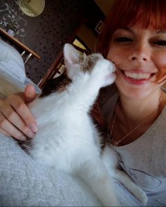 Милая девушка с рыжими волосами держит на руках белого котенка. Теплое и уютное фото, вызывающее положительные эмоции.