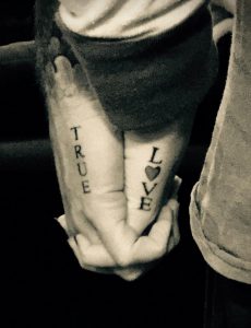 Фото тату на руках, где на одной руке написано 'TRUE', а на другой 'LOVE', с сердцем вместо буквы 'O'.