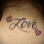 Фото тату на шее с надписью 'Love' и двумя маленькими розовыми сердечками. Нежный и женственный дизайн.