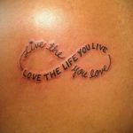 Фото тату на спине с изображением символа бесконечности и надписью 'Live the life you live, Love the life you love'.