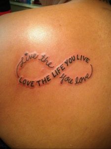 Фото тату на спине с изображением символа бесконечности и надписью 'Live the life you live, Love the life you love'.