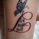 Фото татуировки на ноге с изображением синей бабочки и надписью 'Live Laugh Love'. Красные контуры, детализированный рисунок.