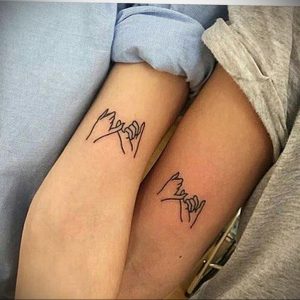 Фото парных татуировок на запястьях. Изображение соединенных мизинцев, выполненное тонкими черными линиями.